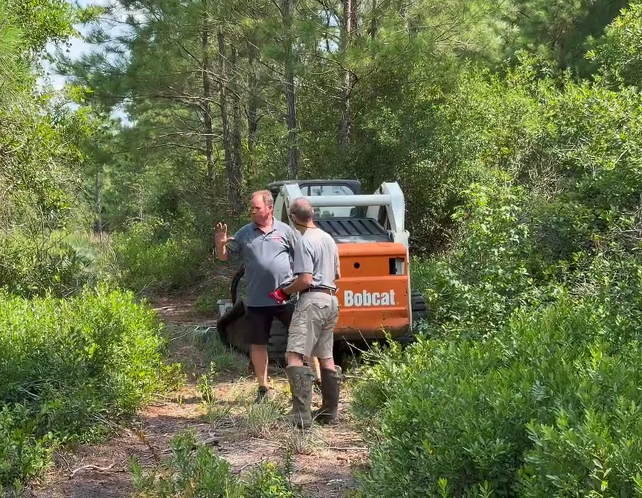 Owner waving beside the Bobcat T300 track loader on a freshly cleared trail near Longs SC